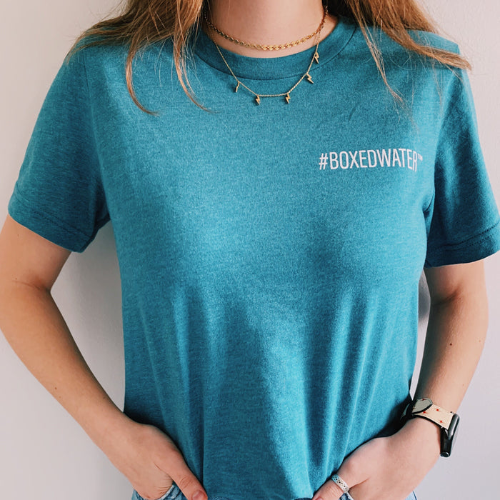 Female wearing teal Boxed Water t-shirt that says #BOXEDWATER