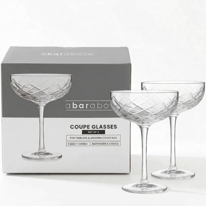 Labeled graphic showing a set of two diamond-cut coupe glasses with product features and branding (details in description).