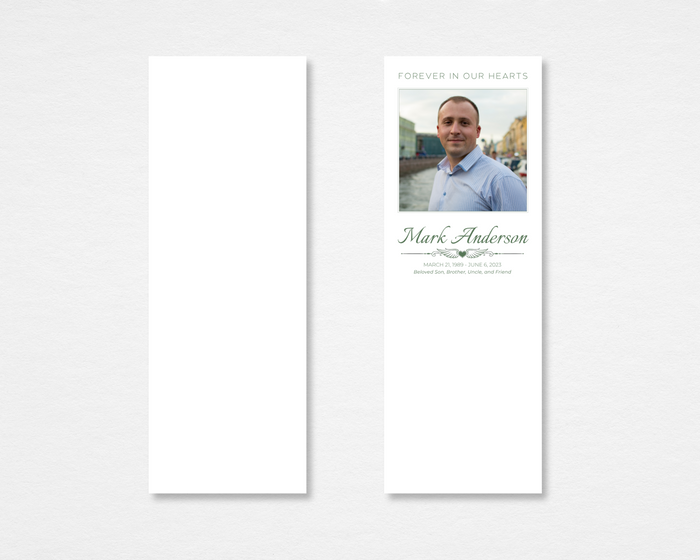 Quiet Classic memorial bookmark — clean white background with rectangular portrait photo placeholder, "Forever in Our Hearts" header in sage green caps, script name, dates, winged heart divider, and italic relationship line on front; plain white back — front and back
