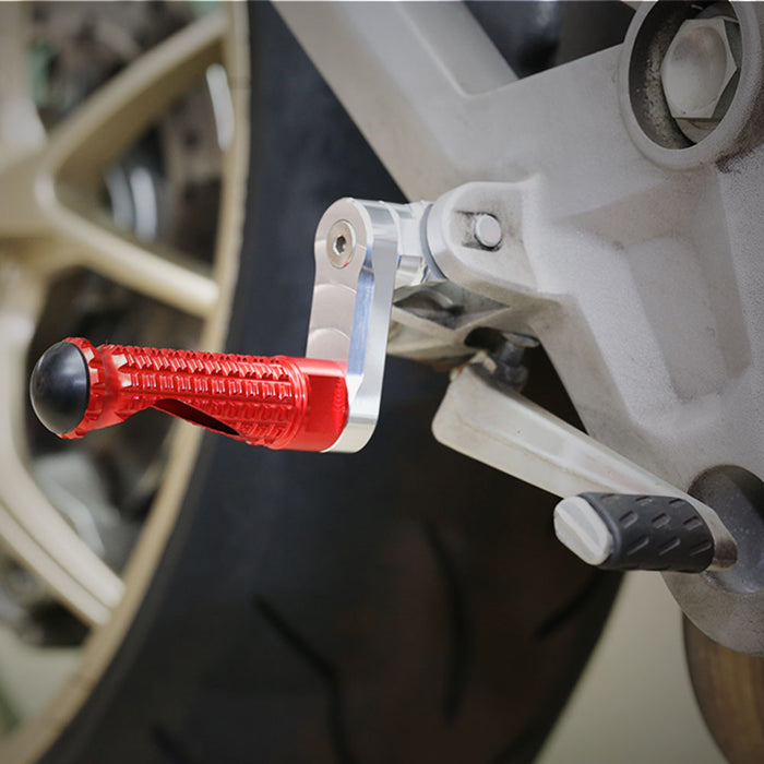 MC Motoparts 40mm extension rear foot pegs for Aprilia Dorsoduro 750 900 Tuono V4R, black metal with textured grip surfaces.