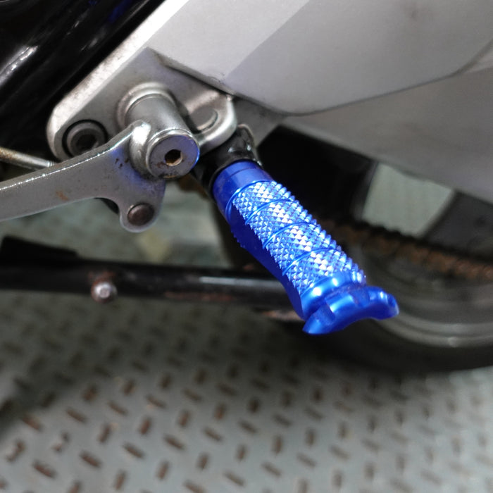 Black MC Motoparts standard rear foot pegs for Yamaha YZF R6 R3 R1 R25 XSR 700 900 motorcycle, mounted on bike frame.