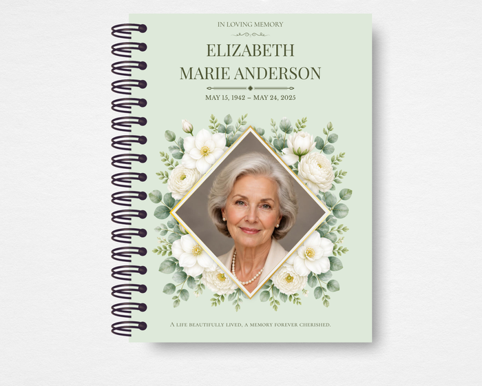 Product mockup of the Sage & Ivory memorial guest book — soft sage green cover with ivory gardenias and eucalyptus sprigs framing a gold diamond portrait frame, name and dates in dark serif type, and a sentiment line along the bottom edge.